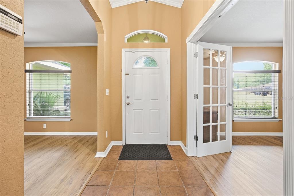 An entryway with tile flooring, a white front door, and wood-look laminate in adjacent rooms — 3539 SE 136TH PLACE, SUMMERFIELD, FL