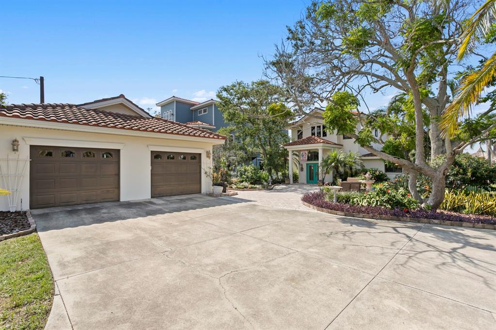 A beige house with a two-car garage and a paved driveway under a blue sky — 1632 SEA BREEZE DRIVE, TARPON SPRINGS, FL
