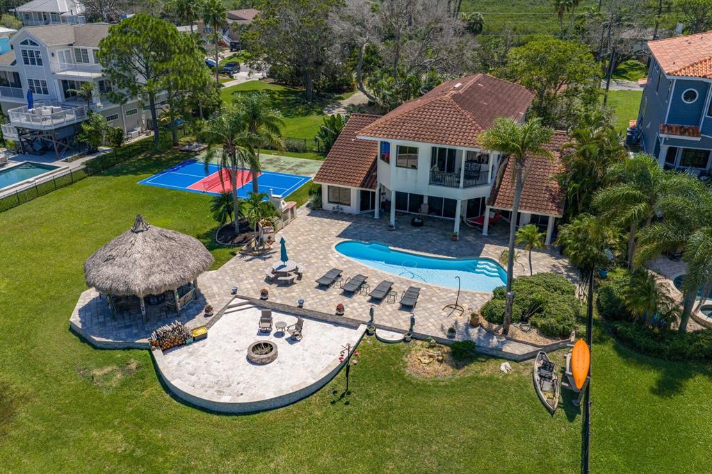 An aerial view of a backyard featuring a swimming pool, tiki hut, and pickleball court — 1632 SEA BREEZE DRIVE, TARPON SPRINGS, FL