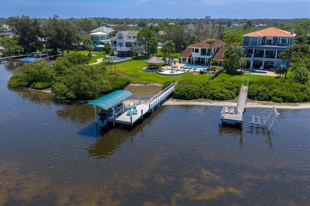 An aerial view shows waterfront houses with private docks and swimming pools along a bay — 1632 SEA BREEZE DRIVE, TARPON SPRINGS, FL