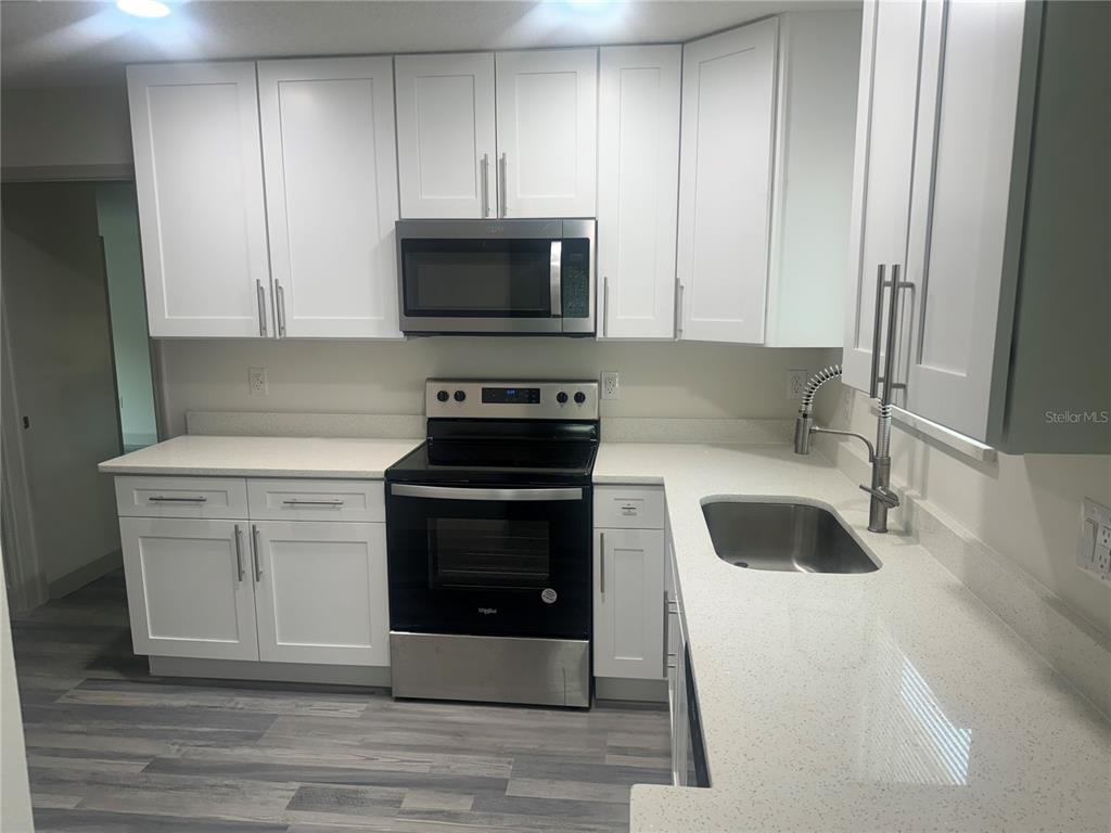 A kitchen featuring white cabinets, stainless steel appliances, and light-colored quartz countertops — 1149 LA SALLE STREET, CLEARWATER, FL