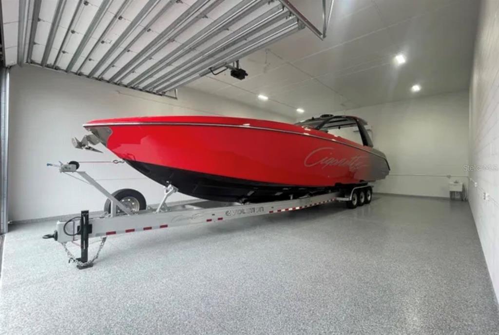 A bright red Cigarette powerboat sits on a trailer inside a spacious, clean garage — 144 ANCHOR ROAD UNIT B-9, ROTONDA WEST, FL