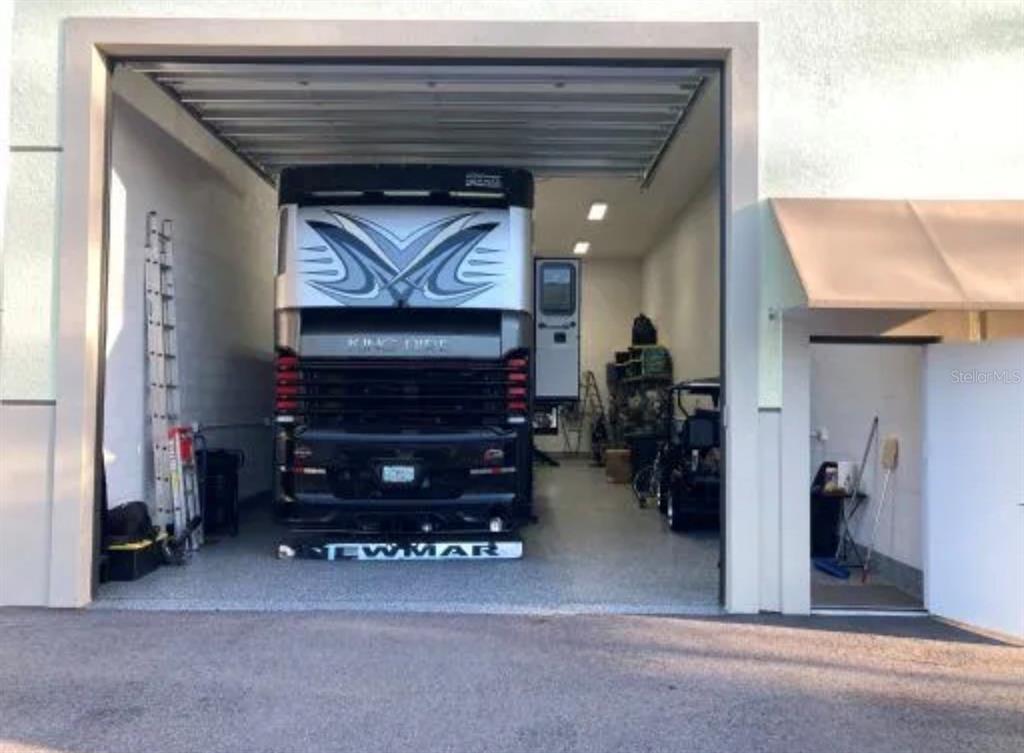 A large garage houses a Newmar motorhome and a golf cart on a concrete floor — 144 ANCHOR ROAD UNIT B-9, ROTONDA WEST, FL
