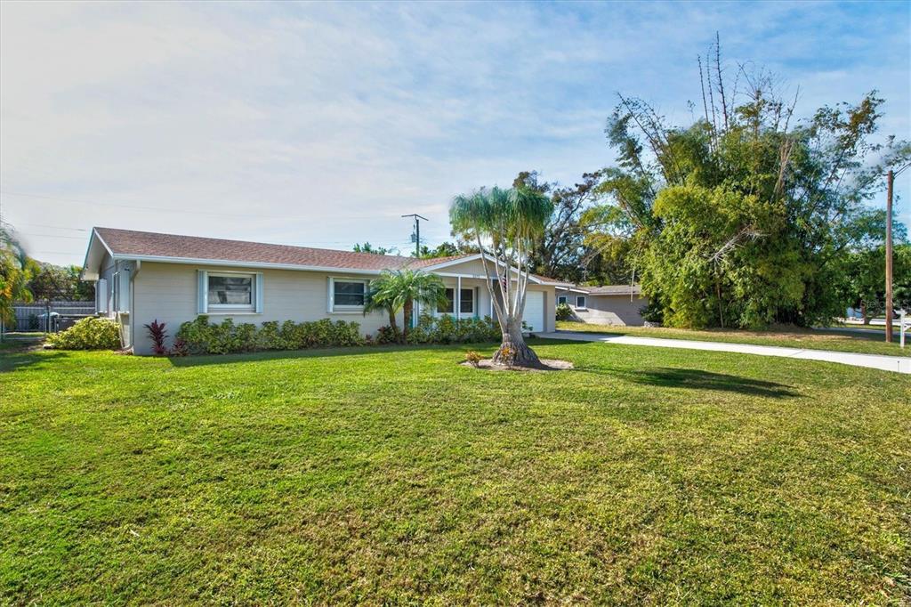 A single-story house with a beige exterior, a large front lawn, and a palm tree — 2572 JEFFERSON CIRCLE, SARASOTA, FL