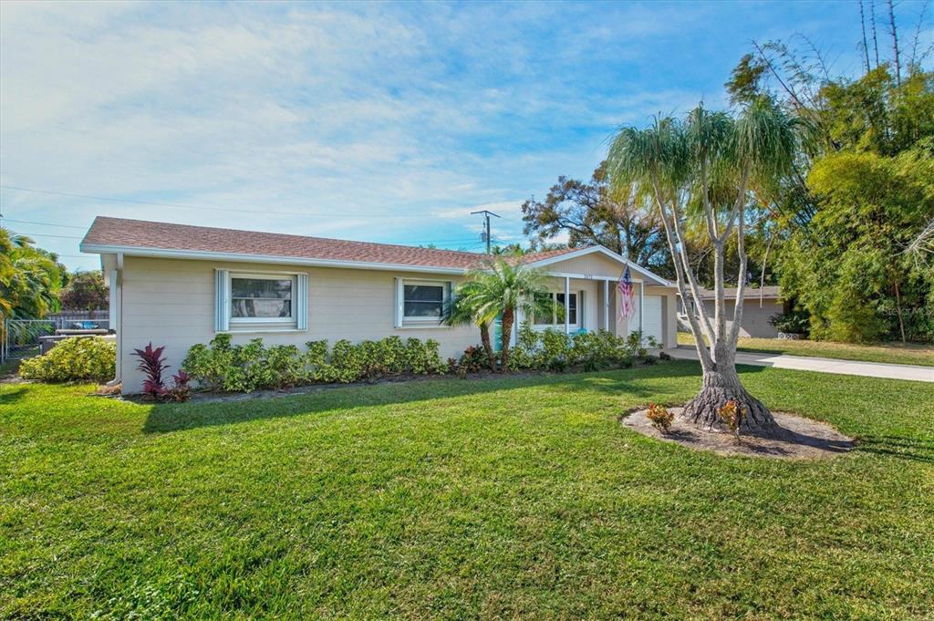 A single-story house with beige siding, a shingled roof, and a palm tree in the yard — 2572 JEFFERSON CIRCLE, SARASOTA, FL