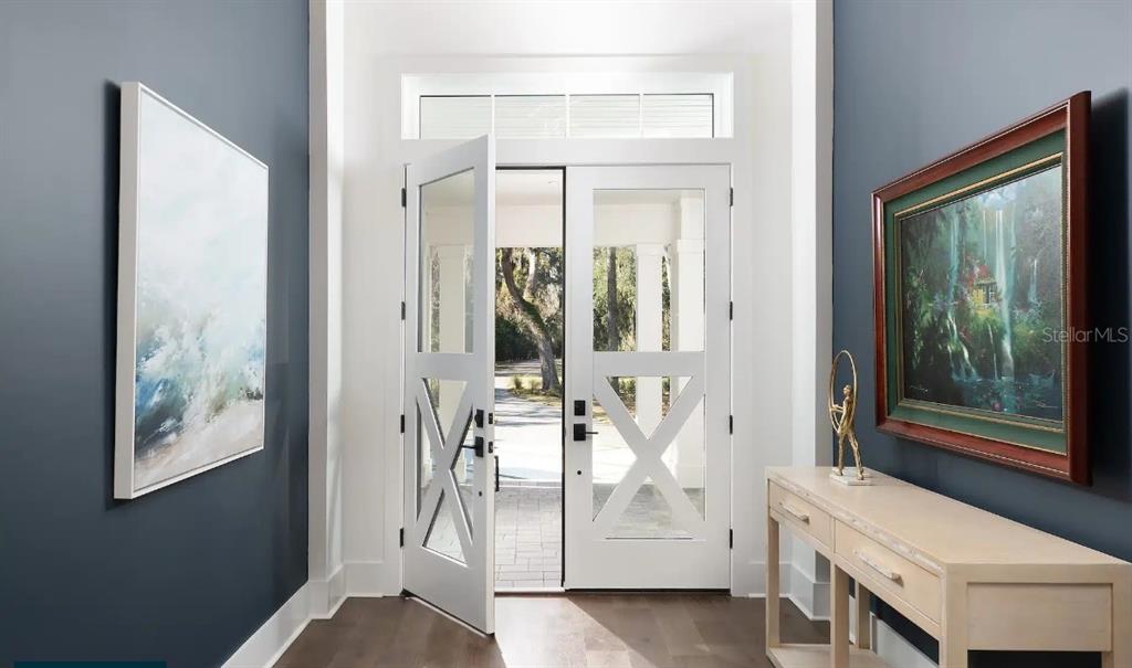 An entryway features double white doors with glass panels, dark blue walls, and a console table — 4299 ROYAL SKY COURT, BROOKSVILLE, FL