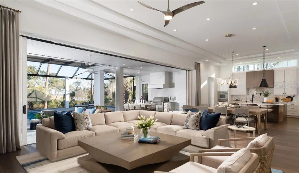 A spacious open-concept living room and kitchen featuring large sliding glass doors to a pool — 4299 ROYAL SKY COURT, BROOKSVILLE, FL