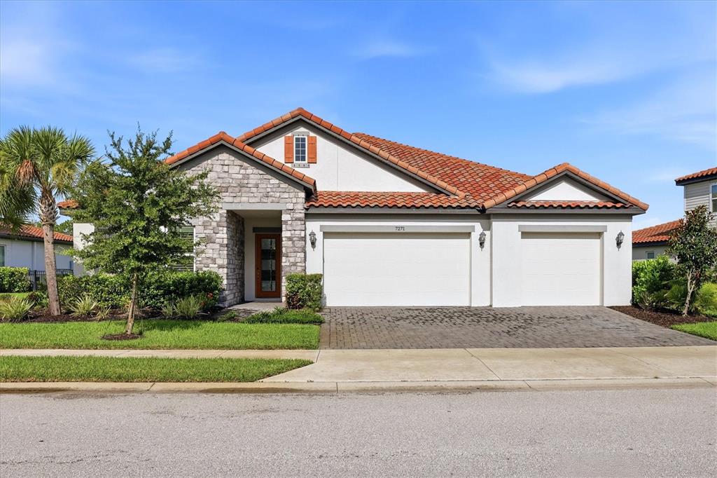 A single-story house with a stone facade, red tile roof, and a three-car garage — 7271 GREAT EGRET BOULEVARD, SARASOTA, FL