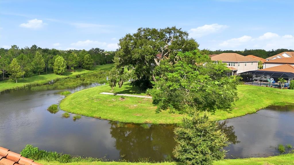 An aerial view shows a grassy peninsula with large trees surrounded by a winding pond — 7271 GREAT EGRET BOULEVARD, SARASOTA, FL