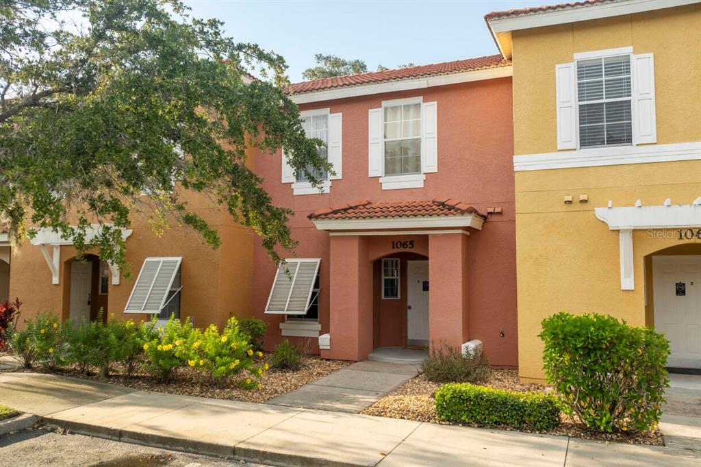 A two-story townhouse with a terracotta-colored facade and a covered entryway — 1065 PARK RIDGE CIRCLE, KISSIMMEE, FL