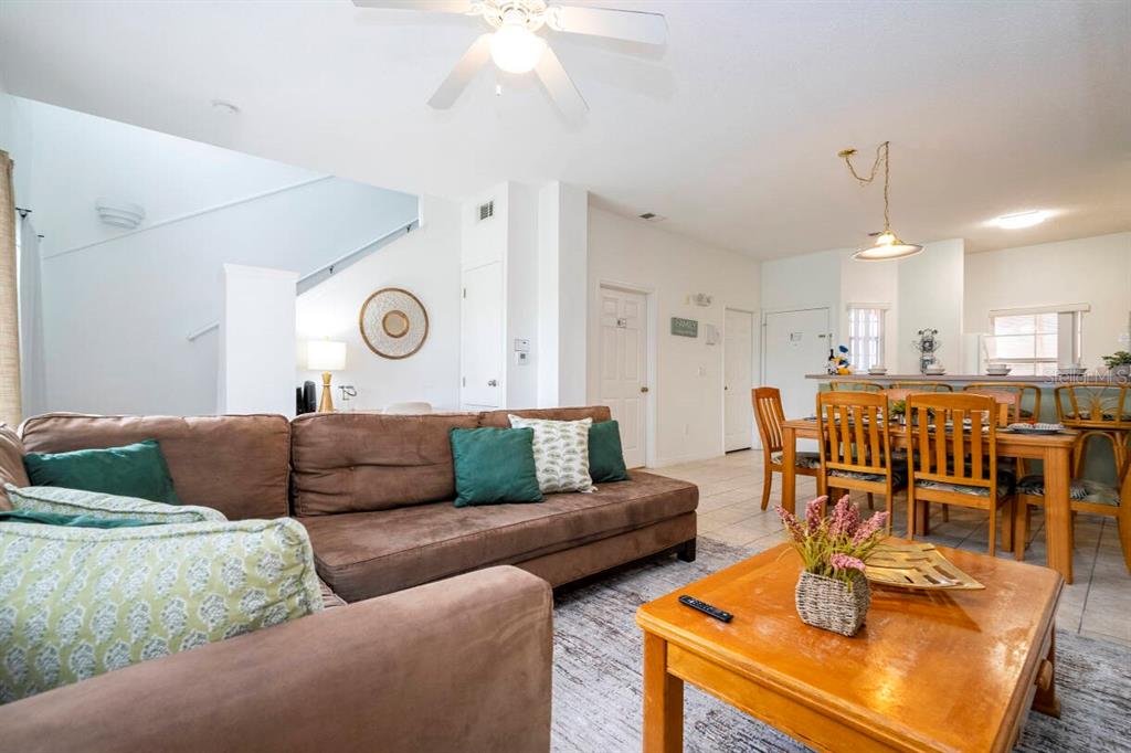 A living room with a brown sectional sofa and a wooden coffee table faces a dining area — 1065 PARK RIDGE CIRCLE, KISSIMMEE, FL