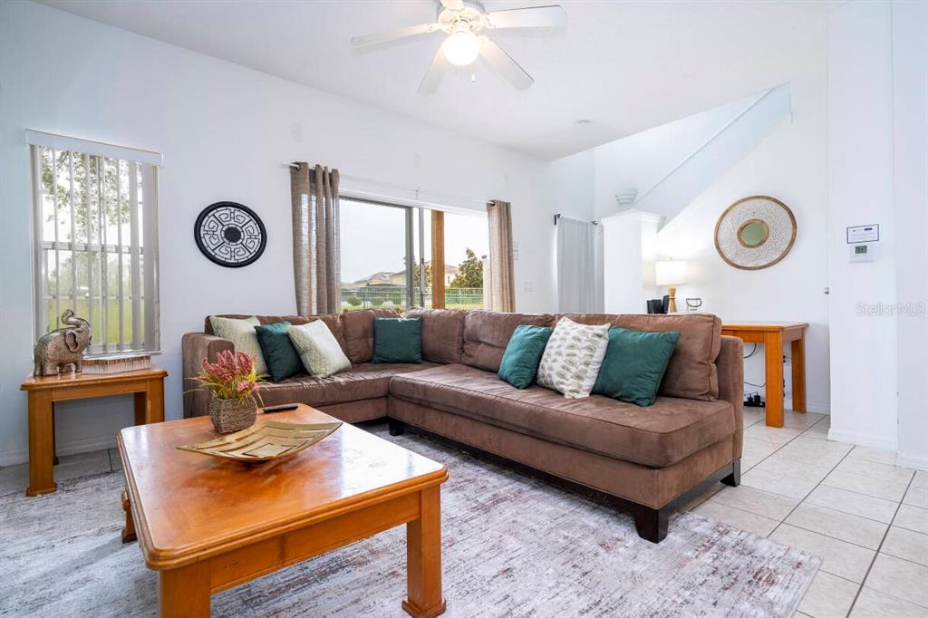 A living room features a brown sectional sofa, a wooden coffee table, and tile flooring — 1065 PARK RIDGE CIRCLE, KISSIMMEE, FL