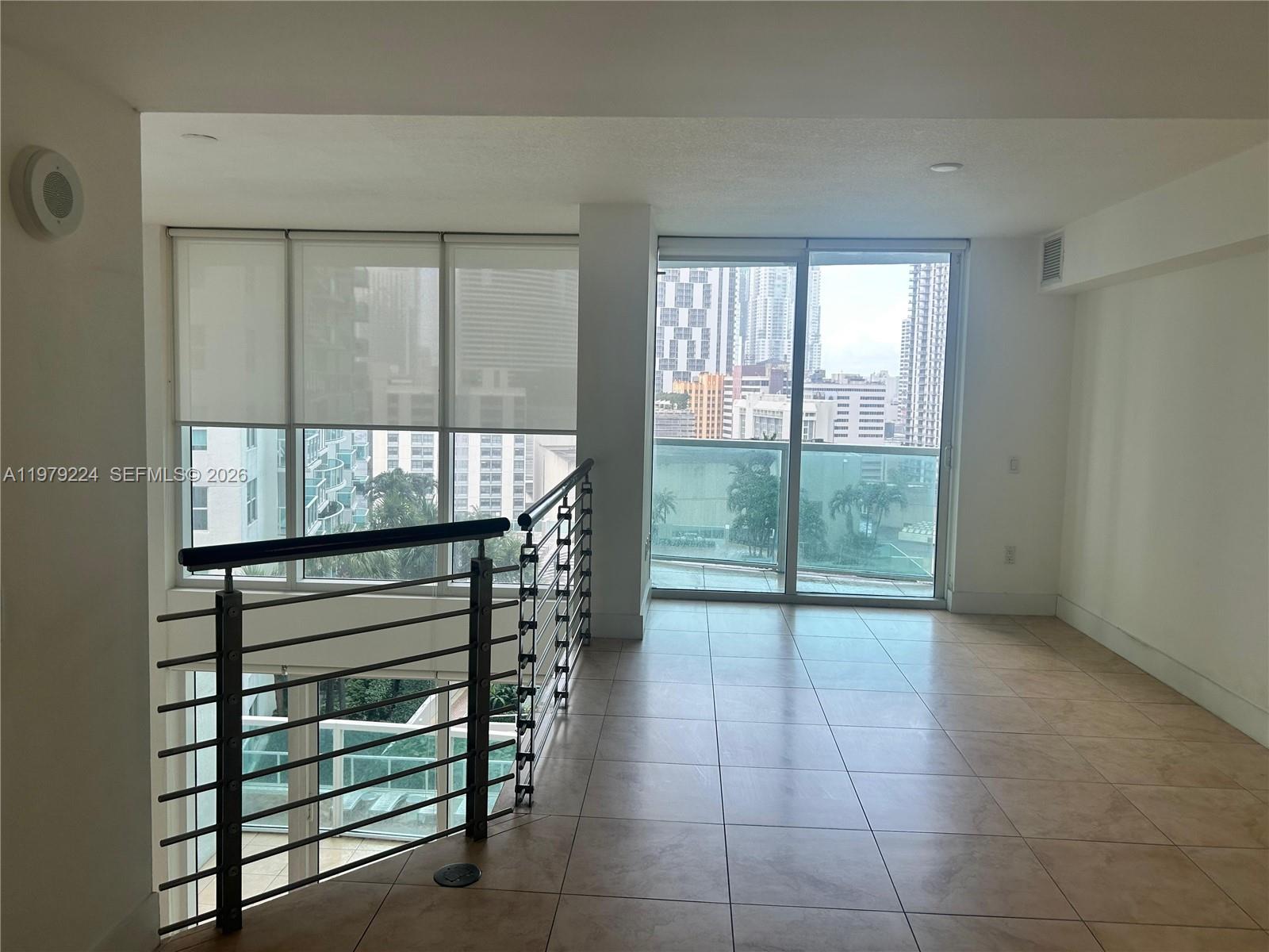 A tiled loft area features a metal railing overlooking a lower level and city views — 41 SE 5th St # 907, Miami FL 33131, MIAMI, FL