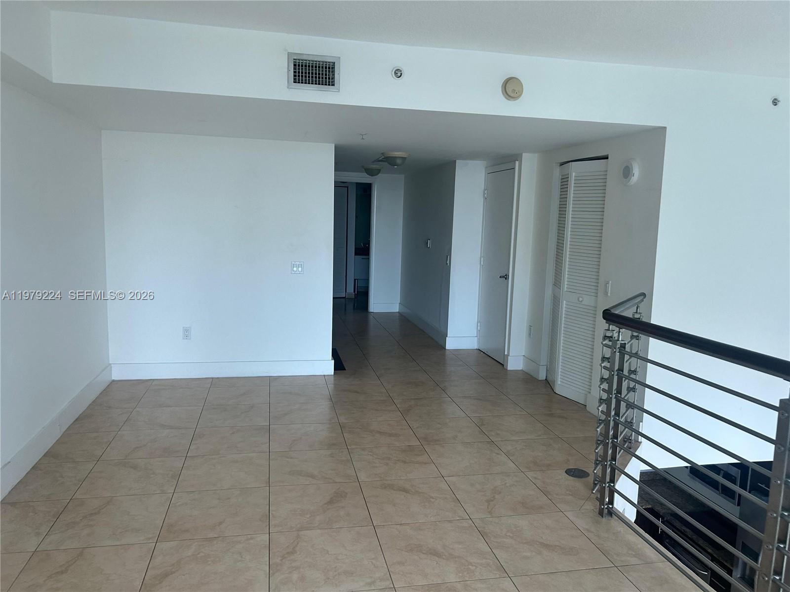 An interior view shows a tiled hallway leading to a doorway with a staircase railing — 41 SE 5th St # 907, Miami FL 33131, MIAMI, FL