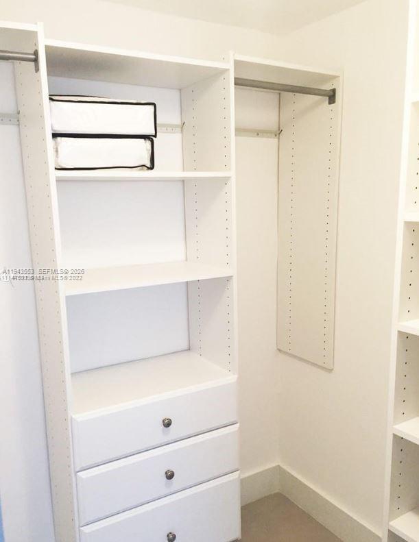 A white walk-in closet features built-in shelving, a hanging rod, and three lower drawers — 100 Lincoln Rd # 426, Miami Beach FL 33139, MIAMI BEACH, FL