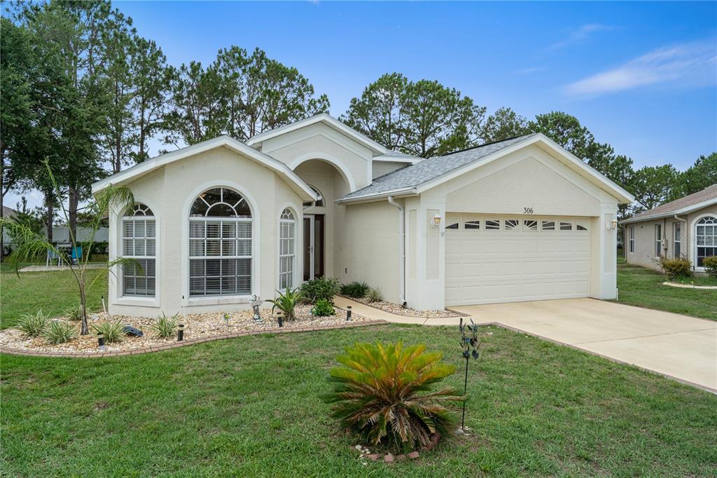 A single-story house with a beige stucco exterior, a two-car garage, and arched windows — 306 BARRINGTON COURT, SPRING HILL, FL