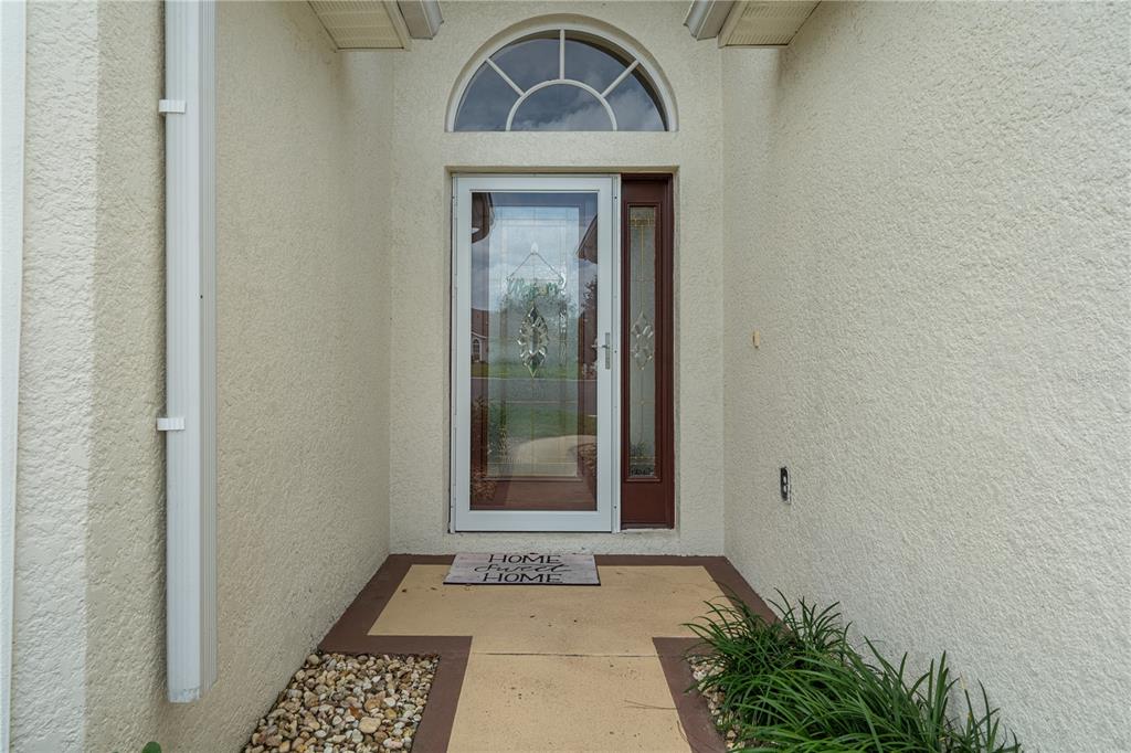 A front entryway features a glass storm door, a sidelight, and an arched transom window — 306 BARRINGTON COURT, SPRING HILL, FL