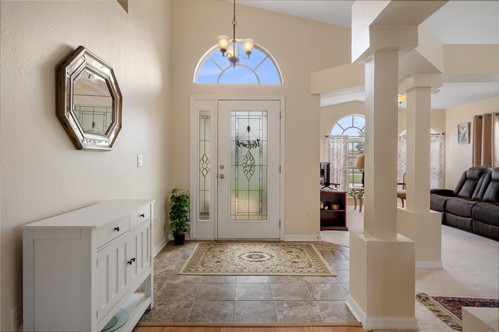 An entryway with tile flooring, a white console table, a front door, and a mirror — 306 BARRINGTON COURT, SPRING HILL, FL