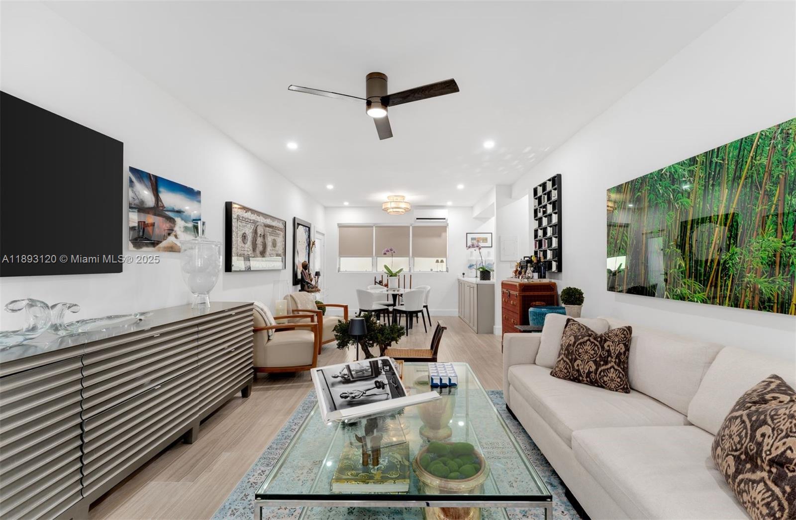 A living room features a white sofa, glass coffee table, and a dining area beyond — 4720 Pine Tree Drive # 2, Miami Beach FL 33140, MIAMI BEACH, FL