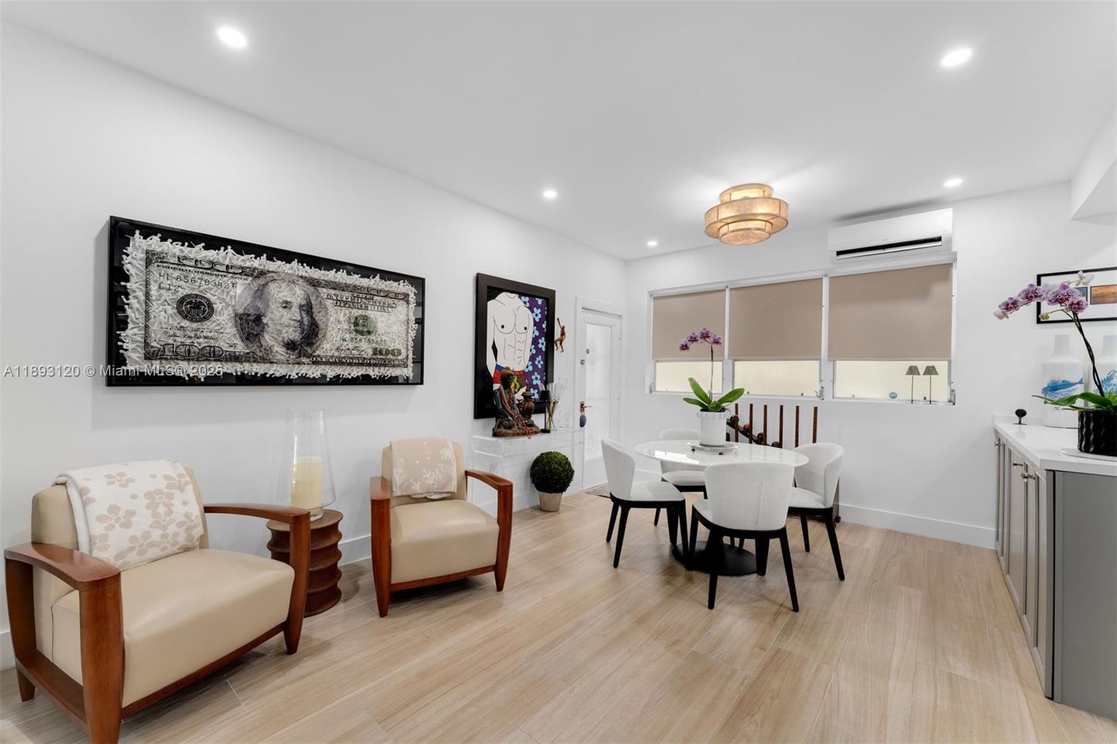 A dining area features a round table, four chairs, two armchairs, and modern wall art — 4720 Pine Tree Drive # 2, Miami Beach FL 33140, MIAMI BEACH, FL