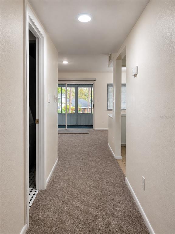 A carpeted hallway leads to a living area with a sliding glass door to a porch — 568 BAHIA CIRCLE UNIT B, OCALA, FL