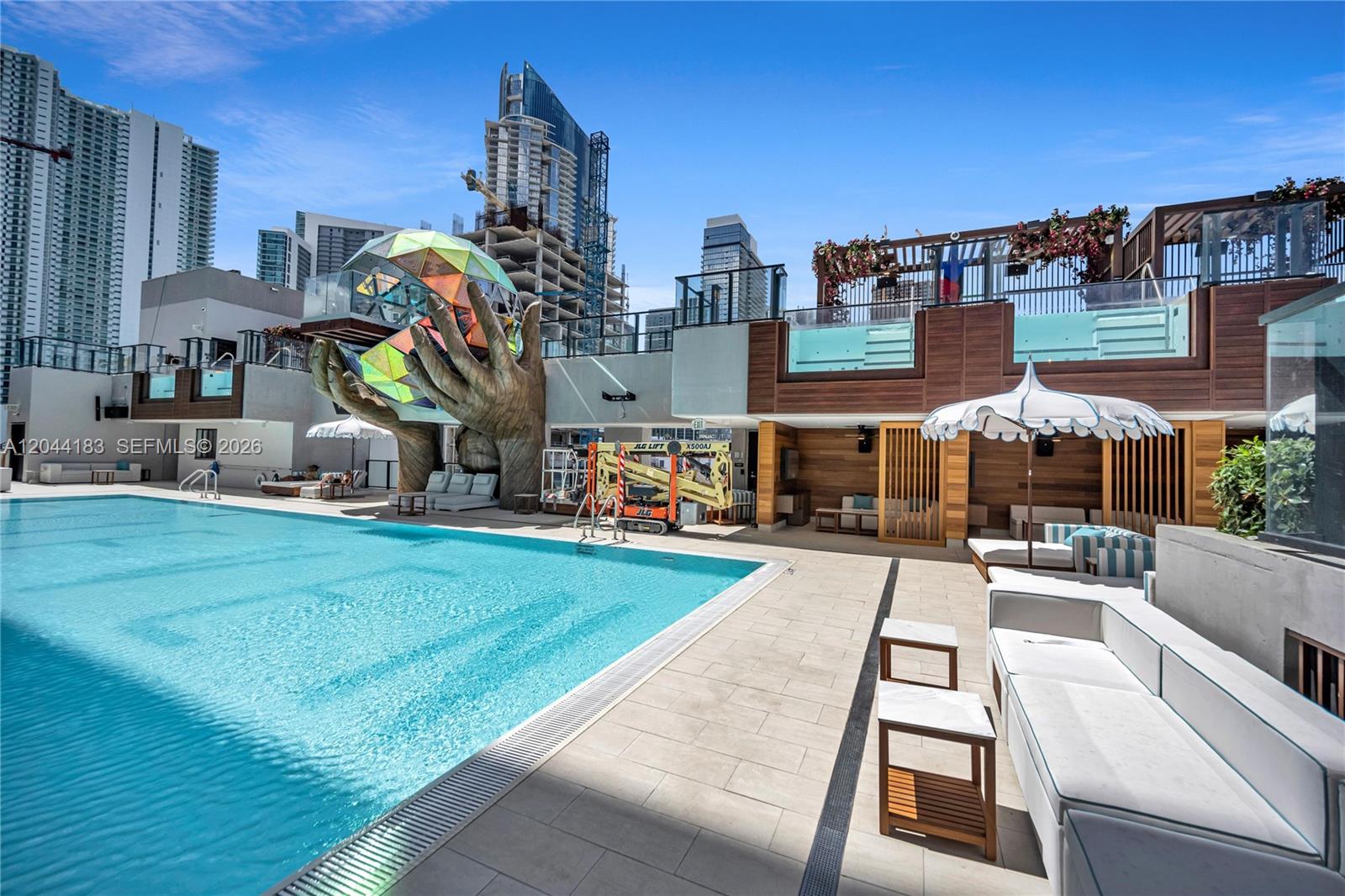 A rooftop swimming pool area features a large sculpture of hands holding a geometric sphere — 20 NE 11th, Miami FL 33132, MIAMI, FL