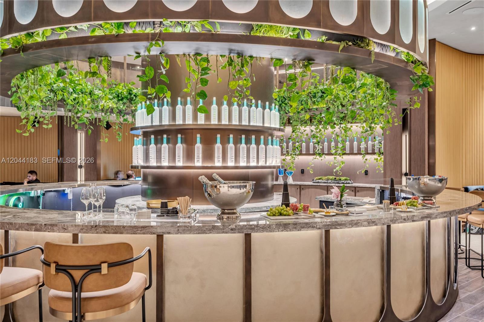 A curved bar features marble countertops, hanging greenery, and shelves stocked with vodka bottles — 20 NE 11th, Miami FL 33132, MIAMI, FL