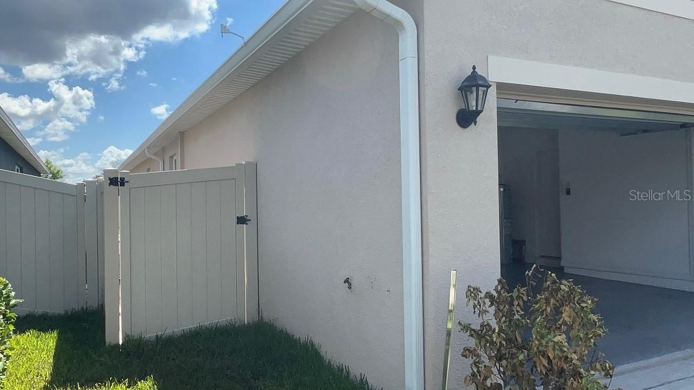 A view of a beige house exterior featuring a white vinyl fence and garage — 864 GUNNISON DRIVE, ORANGE CITY, FL