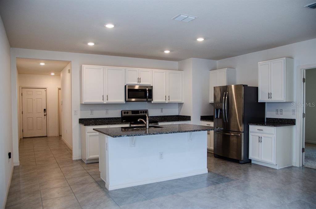 A kitchen with white cabinets, granite countertops, stainless steel appliances, and a central island — 864 GUNNISON DRIVE, ORANGE CITY, FL