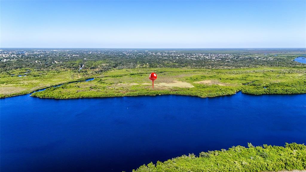 An aerial view shows a red location pin over a grassy area beside a river — 1352 MONTEREY COURT, PUNTA GORDA, FL