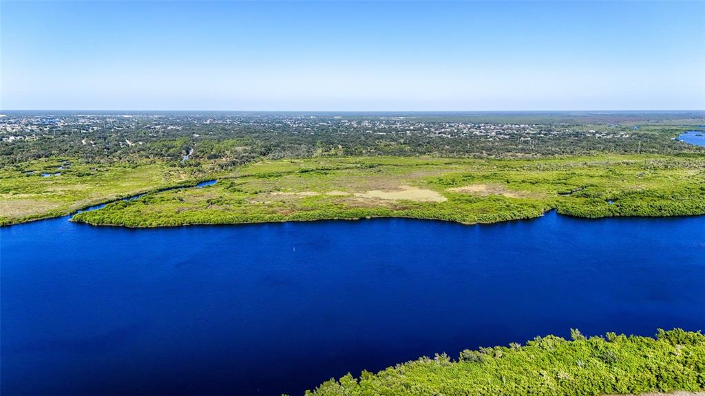 An aerial view shows a wide, dark blue river bordered by dense green marshland — 1352 MONTEREY COURT, PUNTA GORDA, FL