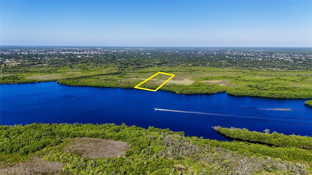 An aerial view shows a yellow-outlined plot of land bordering a river with mangroves — 1352 MONTEREY COURT, PUNTA GORDA, FL