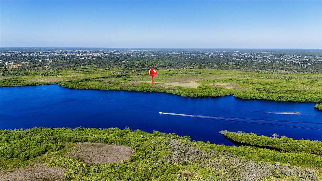 An aerial view shows a boat traveling on a river bordered by dense green vegetation — 1352 MONTEREY COURT, PUNTA GORDA, FL