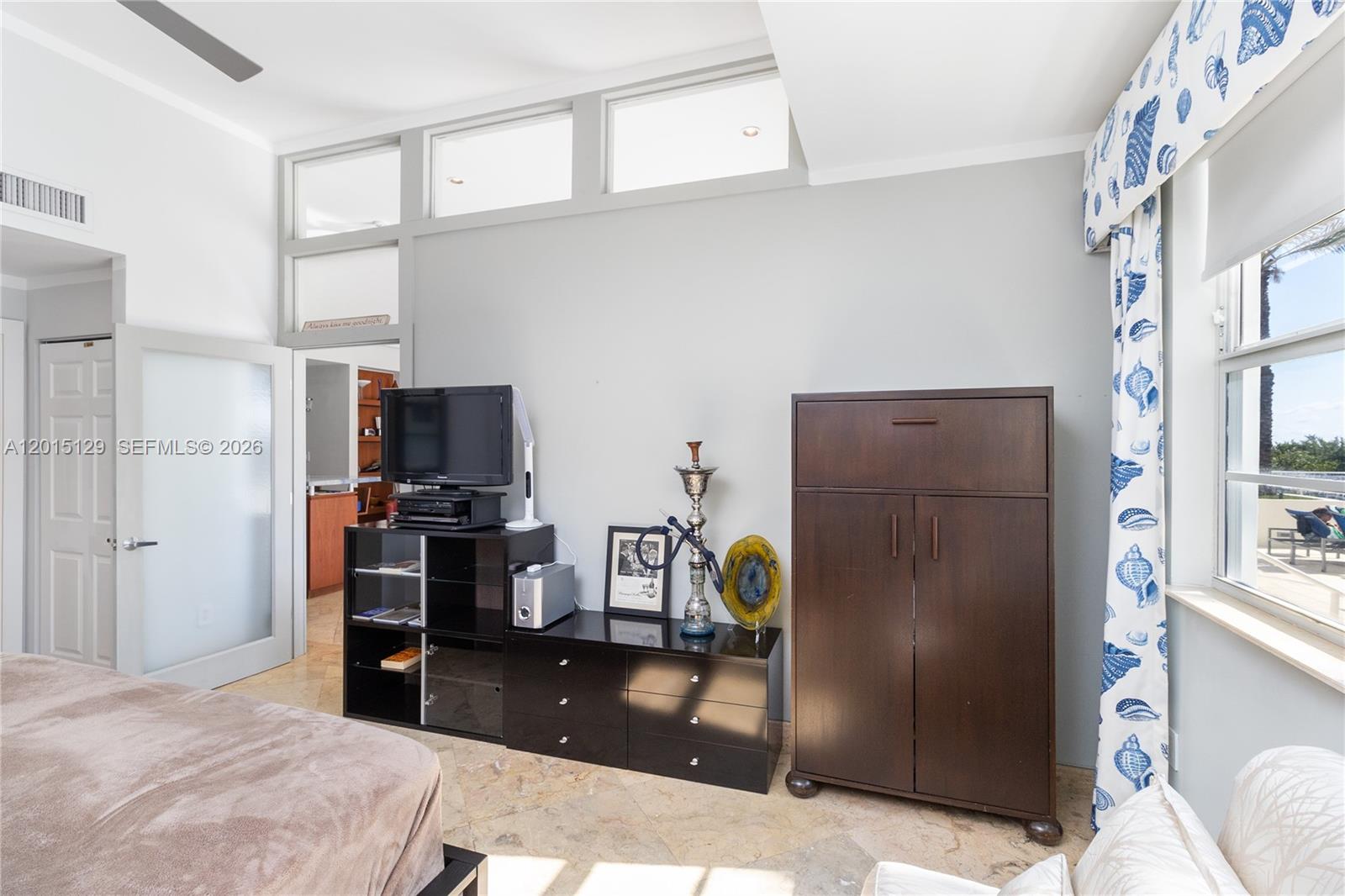 A bedroom features a dark wood armoire, a black media console, and transom windows — 6917 Collins Ave # 103, Miami Beach FL 33141, MIAMI BEACH, FL