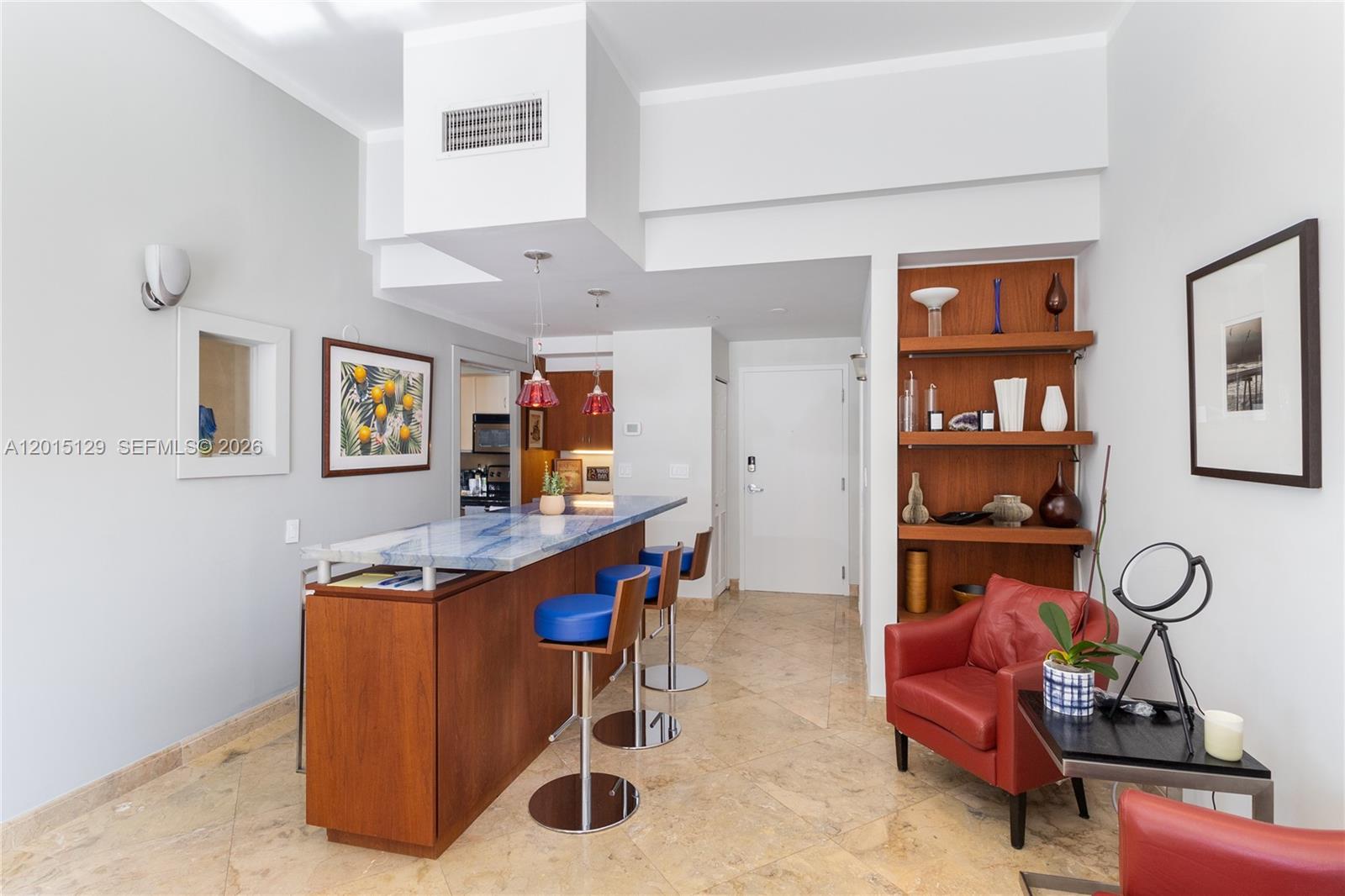A kitchen with a blue marble bar, wooden cabinetry, and a red leather armchair — 6917 Collins Ave # 103, Miami Beach FL 33141, MIAMI BEACH, FL
