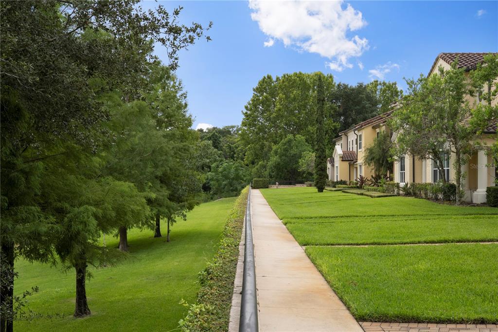 A concrete walkway runs alongside a grassy lawn next to a multi-story residential building — 1132 CHARMING STREET, MAITLAND, FL