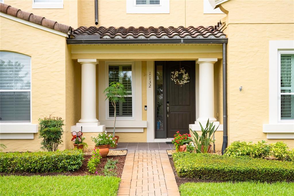 The exterior of a yellow house features a covered entryway with columns and a walkway — 1132 CHARMING STREET, MAITLAND, FL