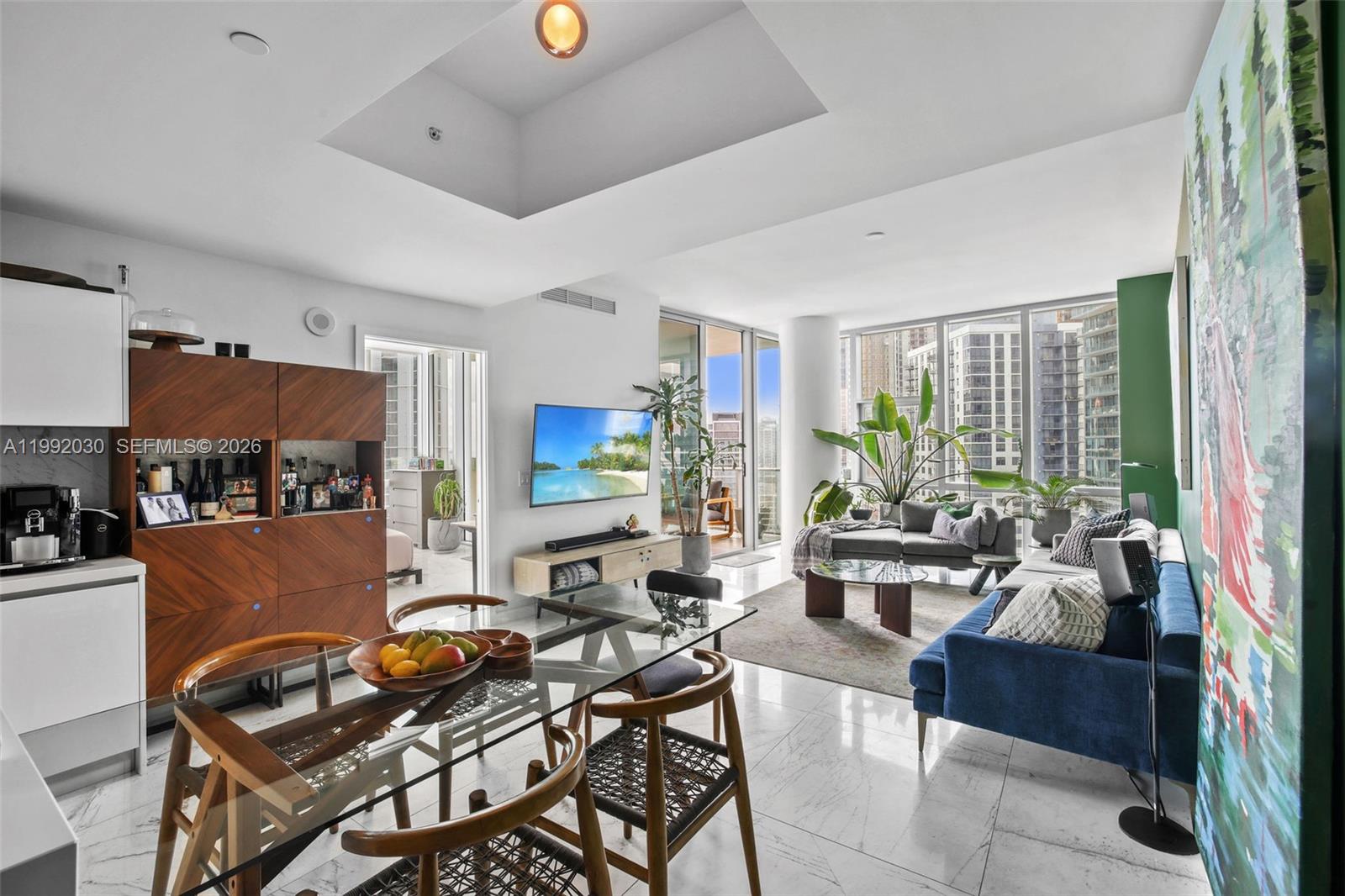 A modern living and dining area with marble floors, floor-to-ceiling windows, and city views — 851 NE 1st Ave # 3211, Miami FL 33132, MIAMI, FL