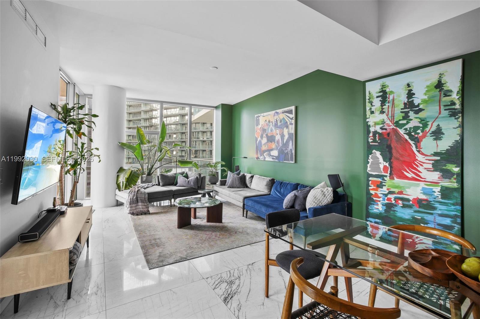 A living room features a green accent wall, a blue sectional sofa, and marble flooring — 851 NE 1st Ave # 3211, Miami FL 33132, MIAMI, FL