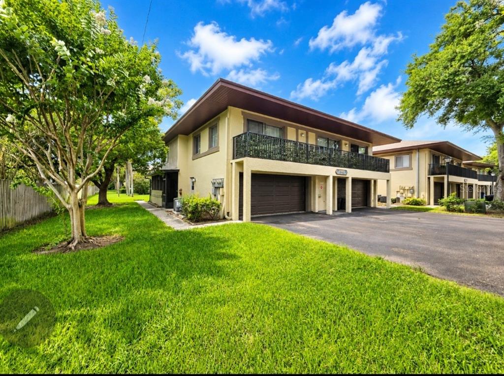 A two-story building exterior features a ground-level two-car garage and an upper-level balcony — 2935 LICHEN LANE UNIT C, CLEARWATER, FL