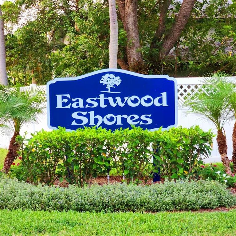 A two-story tan building with a balcony, garage doors, and a grassy yard — 2935 LICHEN LANE UNIT C, CLEARWATER, FL