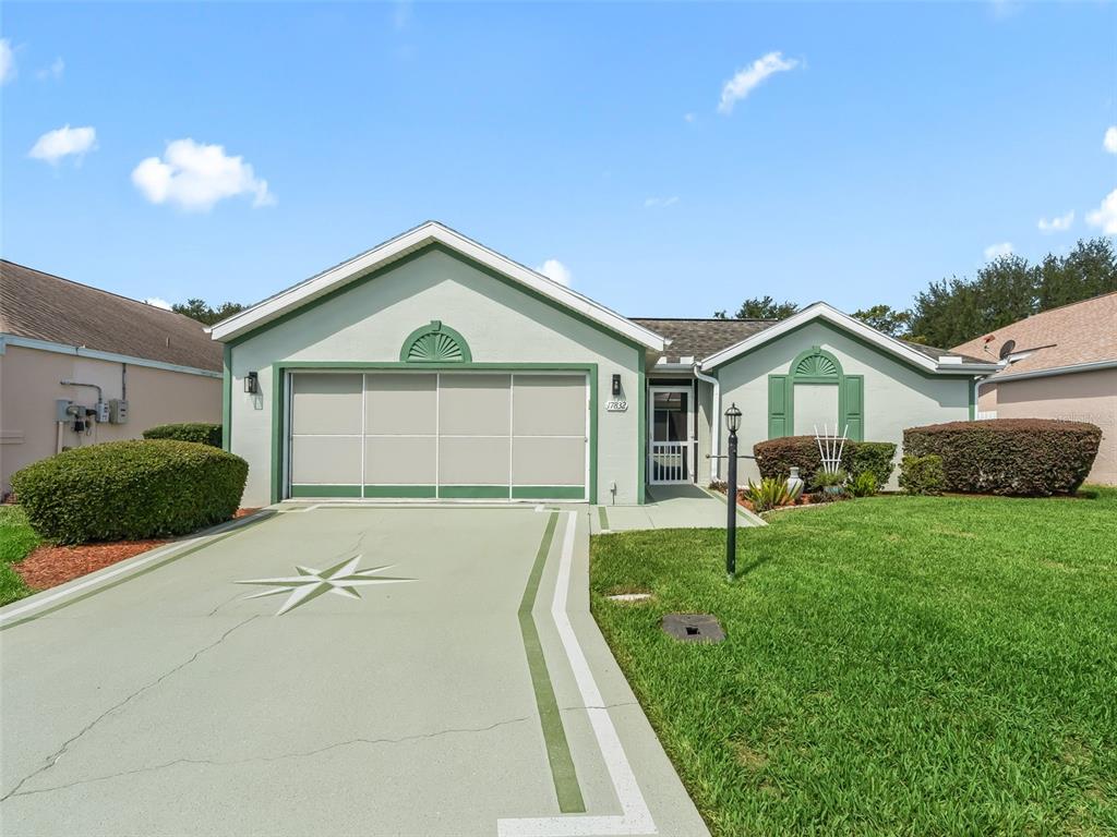 A single-story house features a painted driveway with a compass design and green trim — 17832 SE 115TH COURT, SUMMERFIELD, FL