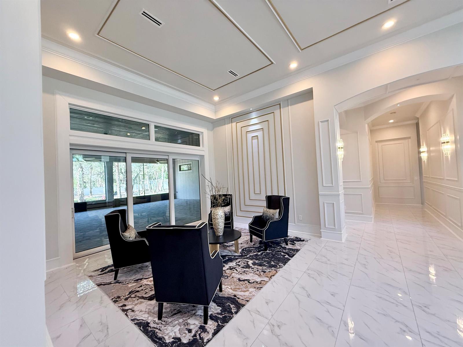 A bright living area features dark armchairs on a patterned rug and marble floors — 145 24th Avenue, Vero Beach FL 32962, VERO BEACH, FL