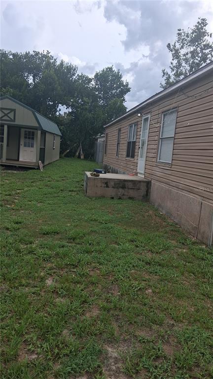 A side view of a mobile home with a concrete porch and a small shed — 6980 NE 4TH LANE, OCALA, FL