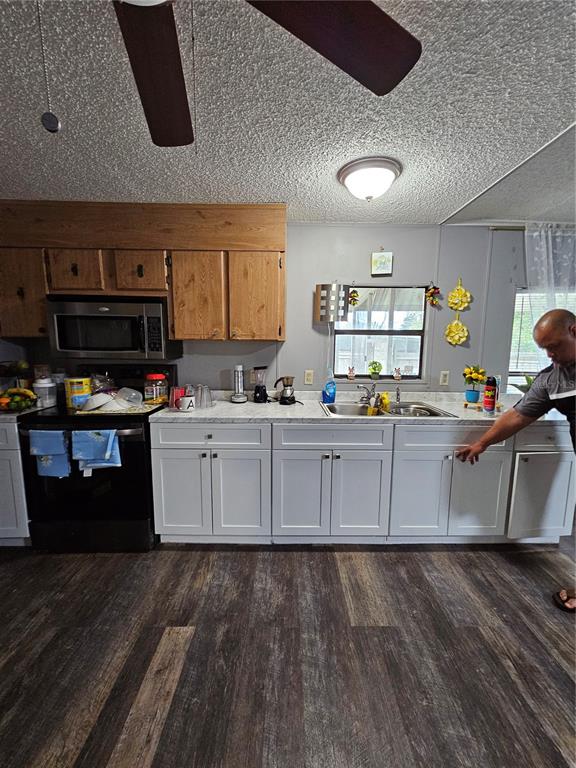 A kitchen features white lower cabinets, wood upper cabinets, a black stove, and wood-look flooring — 6980 NE 4TH LANE, OCALA, FL