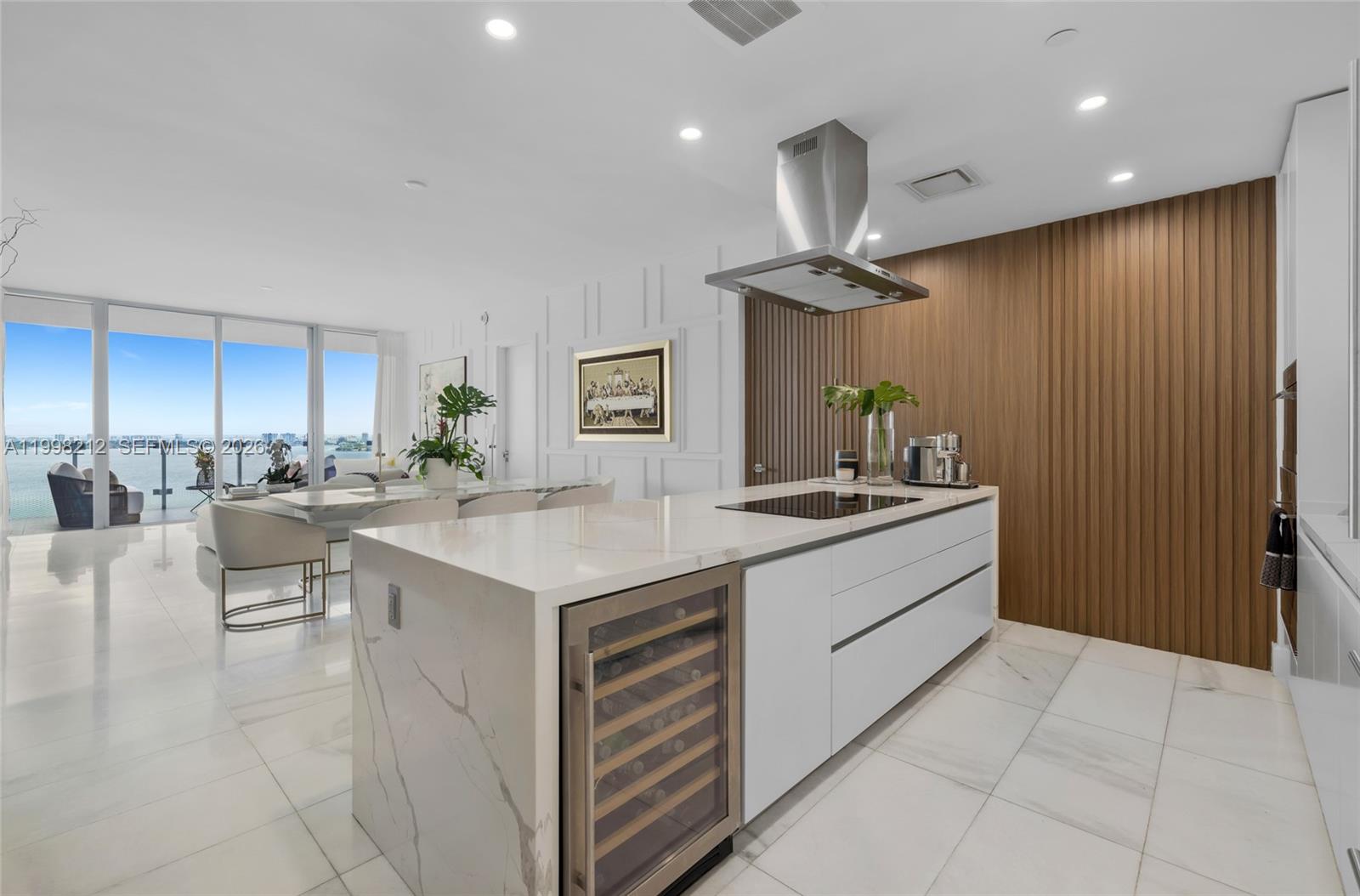 A modern kitchen features a marble-topped island with a wine cooler and wood-paneled accent wall — 700 NE 26th Ter # 2202, Miami FL 33137, MIAMI, FL