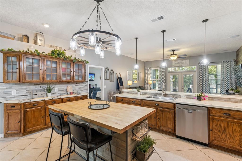 A kitchen features wood cabinets, a butcher block island, and a wagon wheel chandelier — 1405 WINTERVILLE STREET, DELTONA, FL