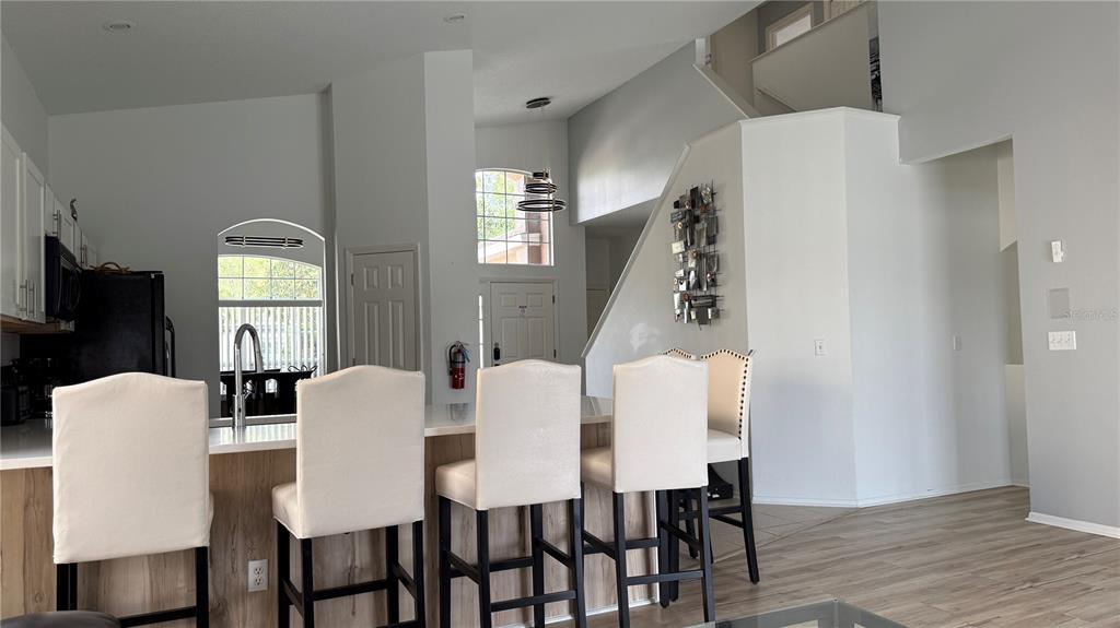 A kitchen island with four white chairs sits in a room with high ceilings — 513 BAILEY CIRCLE, DAVENPORT, FL