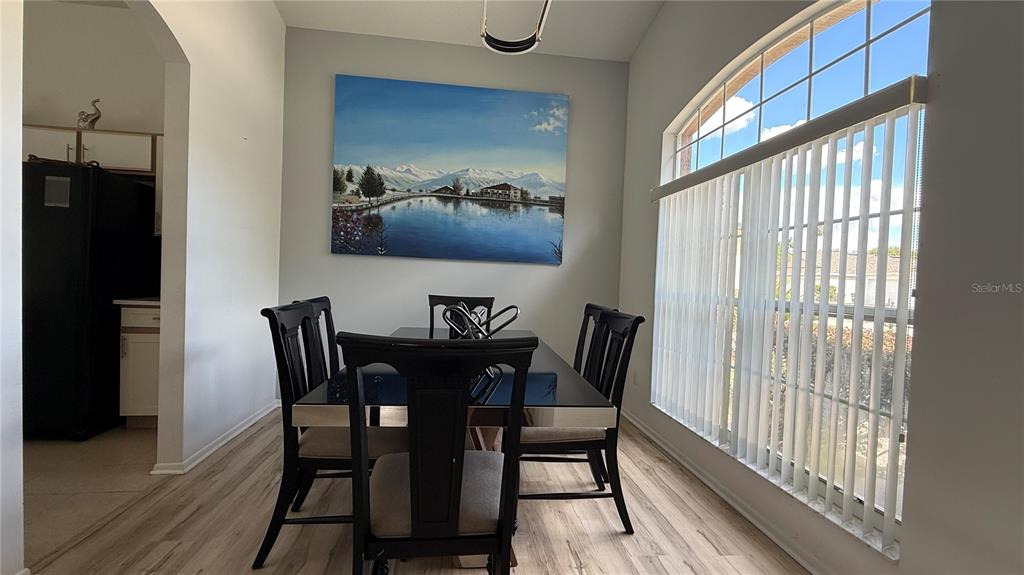 A dining room features a dark table, matching chairs, light wood flooring, and a large painting — 513 BAILEY CIRCLE, DAVENPORT, FL
