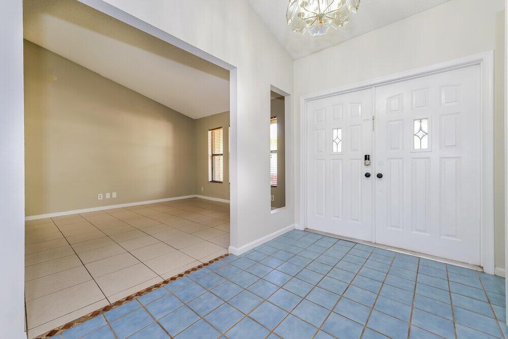 An entryway with blue tile flooring leads to a living room with beige tile floors — WELLINGTON, FL